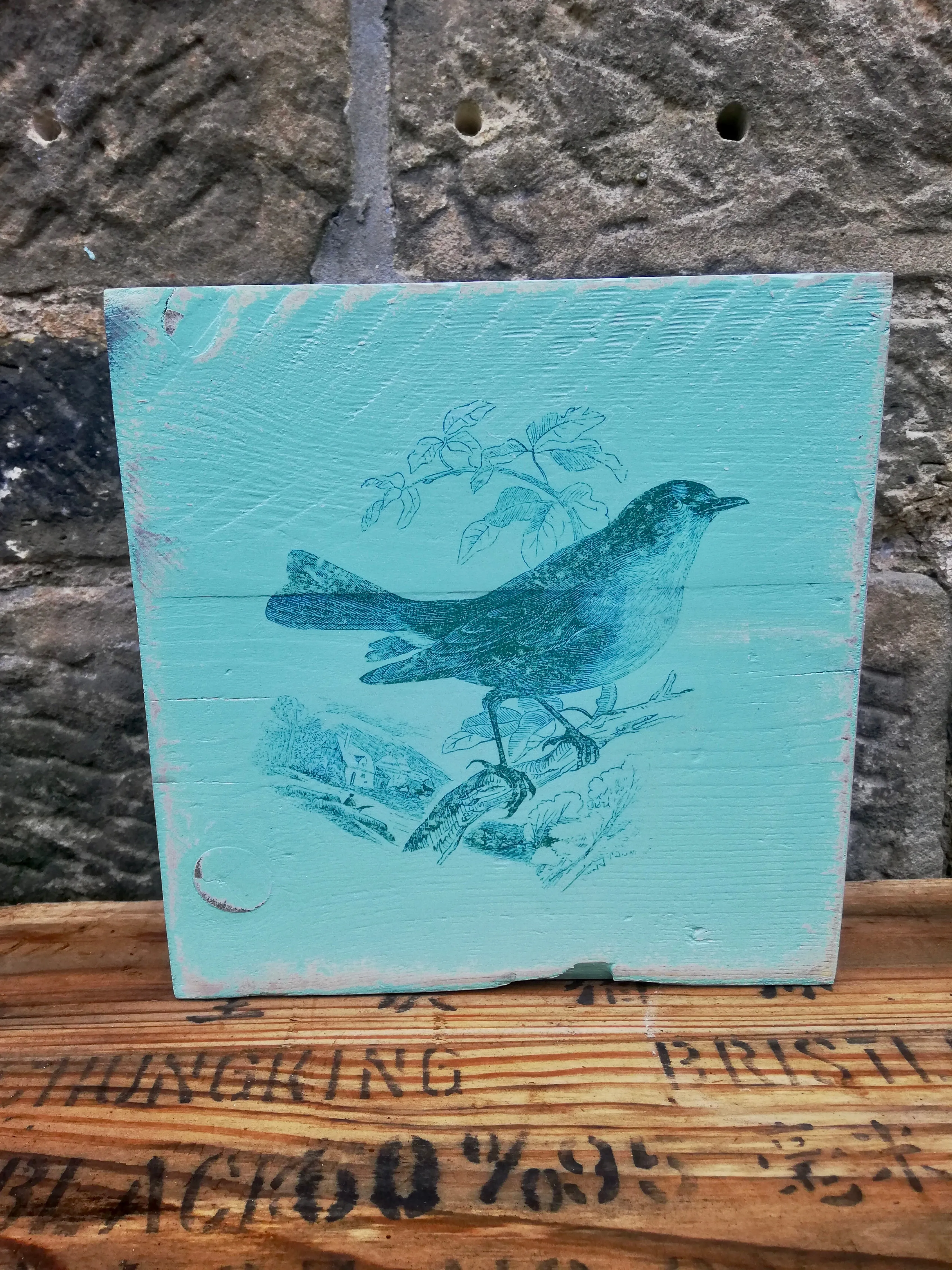 Painted wooden art block with bird design.