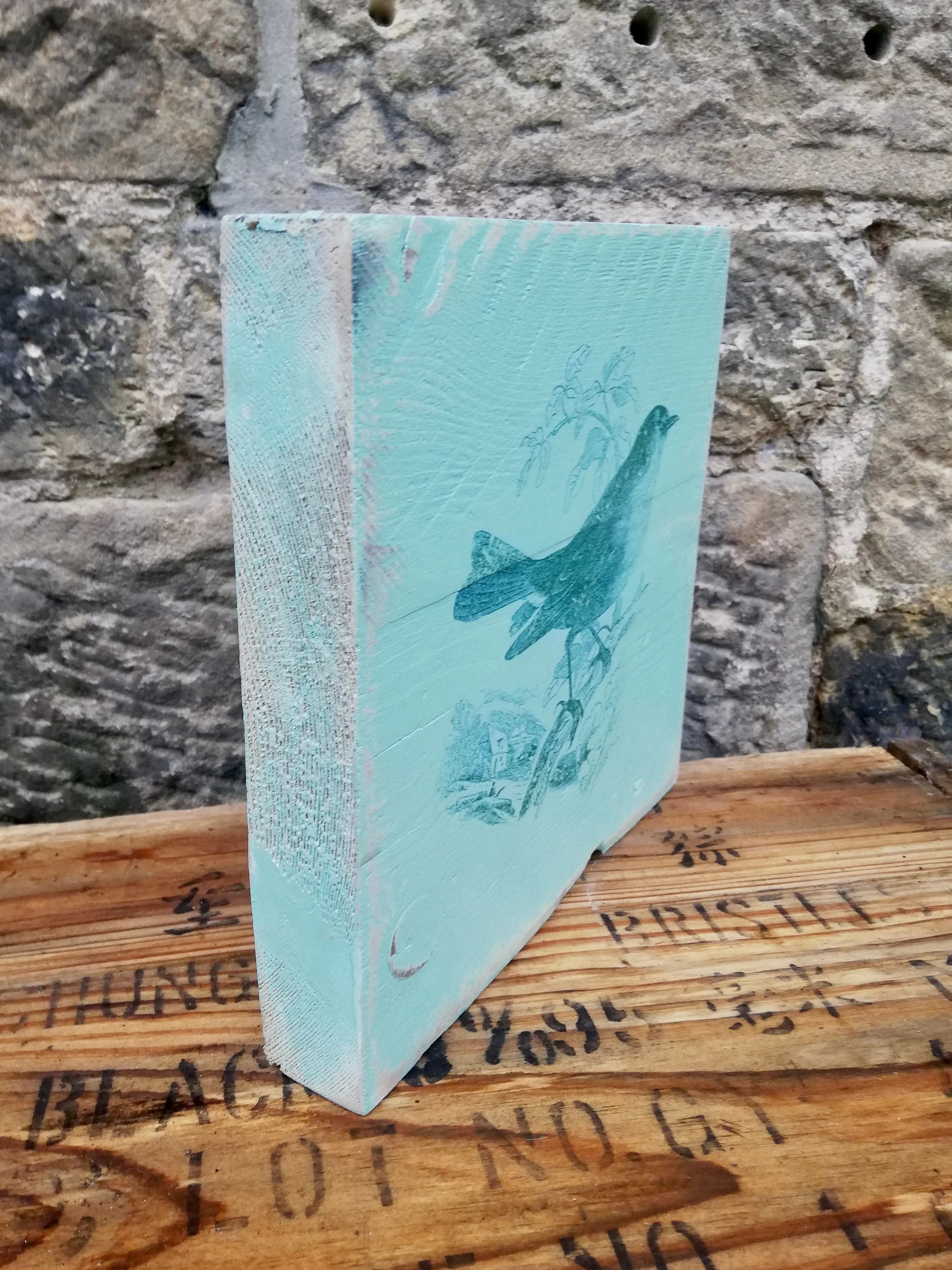 Painted wooden art block with bird design.